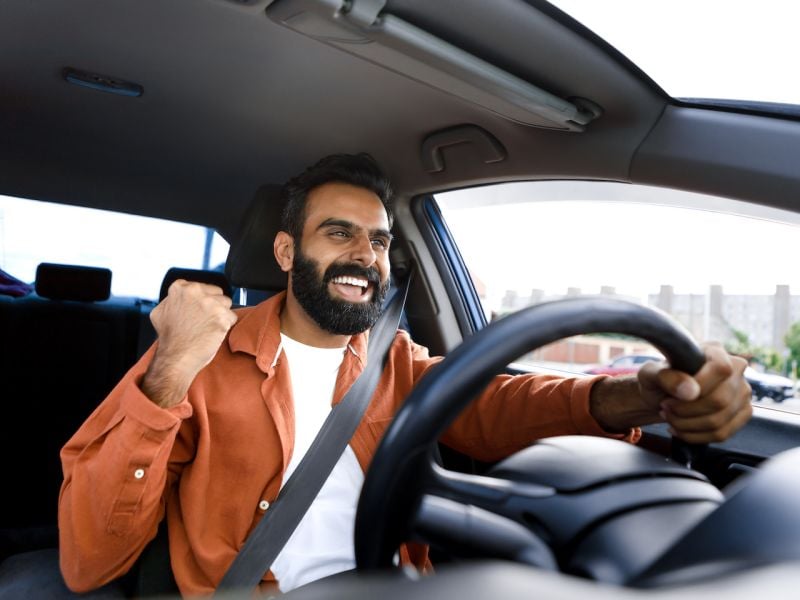 Excited Middle Eastern guy sitting in car gesturing yes