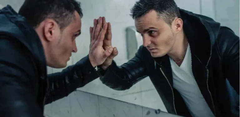 Troubled young man confronting his reflection in mirror after making serious mistake