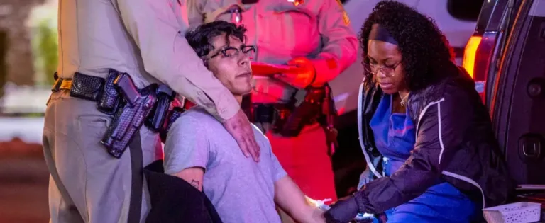 Police officer supervising as nurse draws blood from DUI suspect at roadside stop