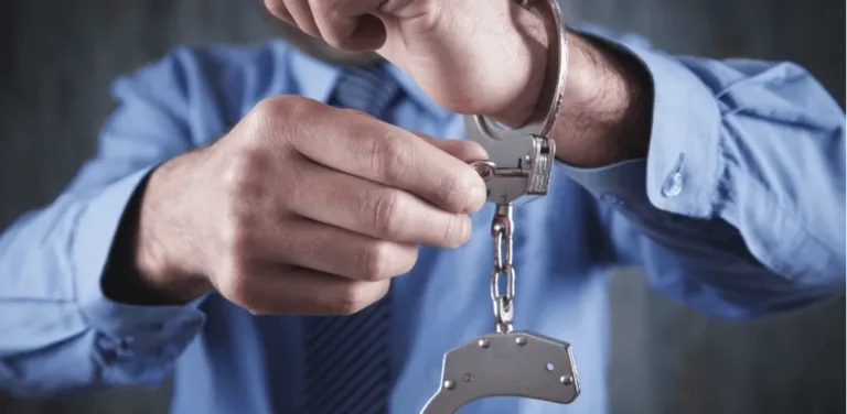 Person in blue shirt unlocking metal handcuffs with a small key