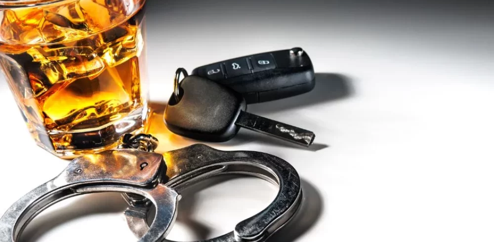 Whiskey glass, car keys and handcuffs symbolizing a drunk driving arrest.