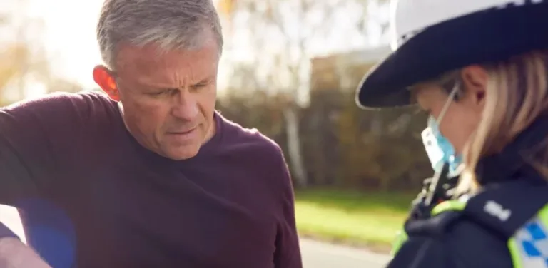 Police officer speaking with a driver on the side of the road.
