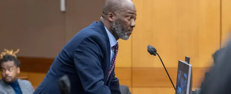 Attorney in blue suit speaking at courtroom podium during legal proceedings.