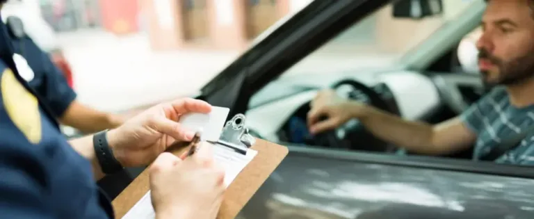 Police officer writes a traffic ticket while driver waits in his car.