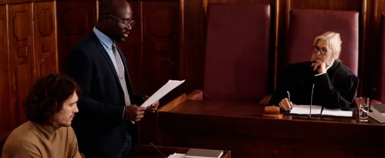 Defense lawyer reading a document in court as the judge listens from the bench
